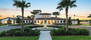 A hotel with a central fountain, palm trees, and a clear sky.