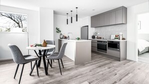 Une cuisine moderne avec des meubles gris, un îlot central et un coin repas avec des chaises grises.