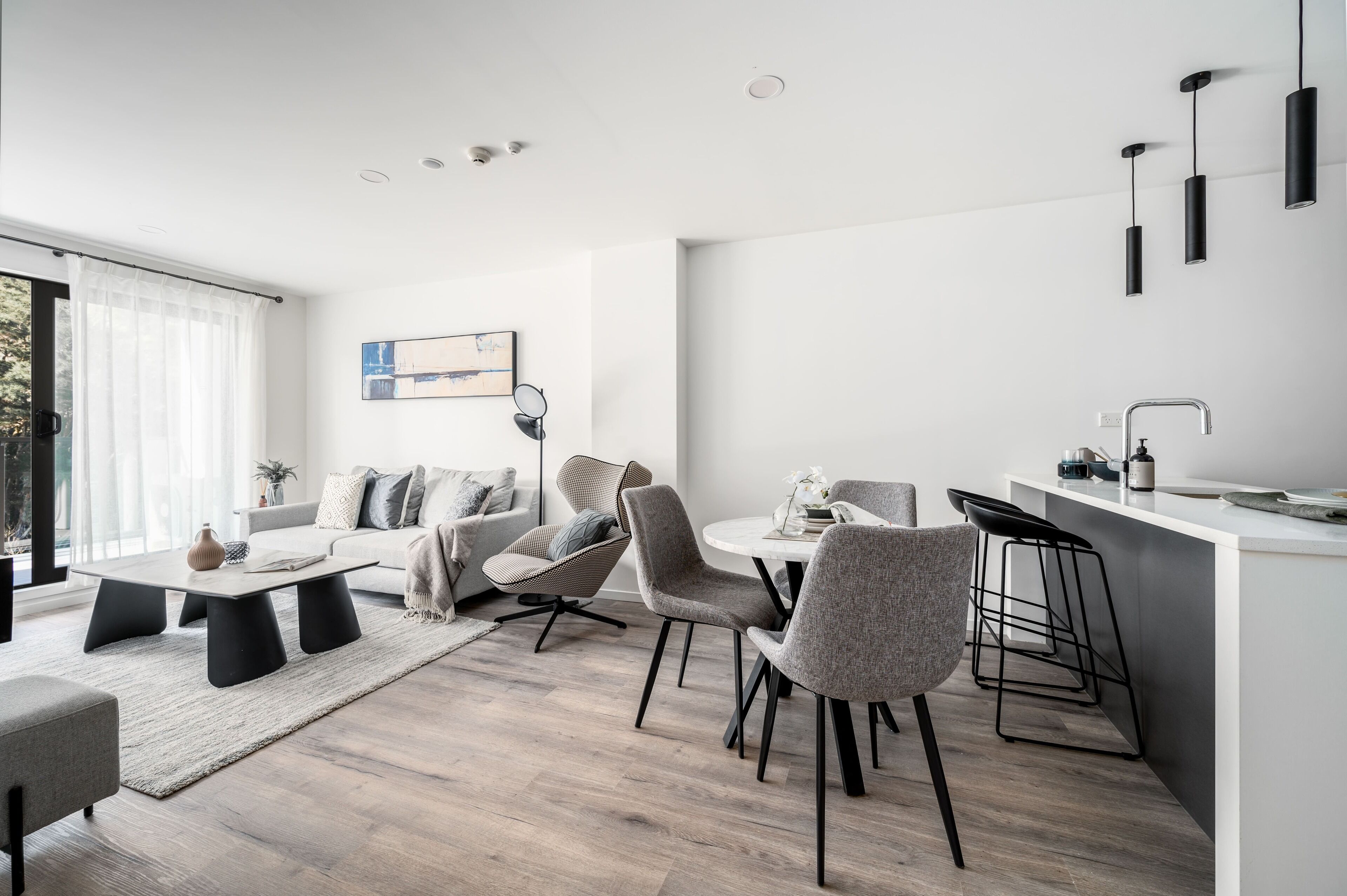 Una sala de estar moderna con un sofá, sillas, una mesa de centro y una zona de comedor con barra.