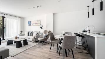 Una sala de estar moderna con un sofá, sillas, una mesa de centro y una zona de comedor con barra.