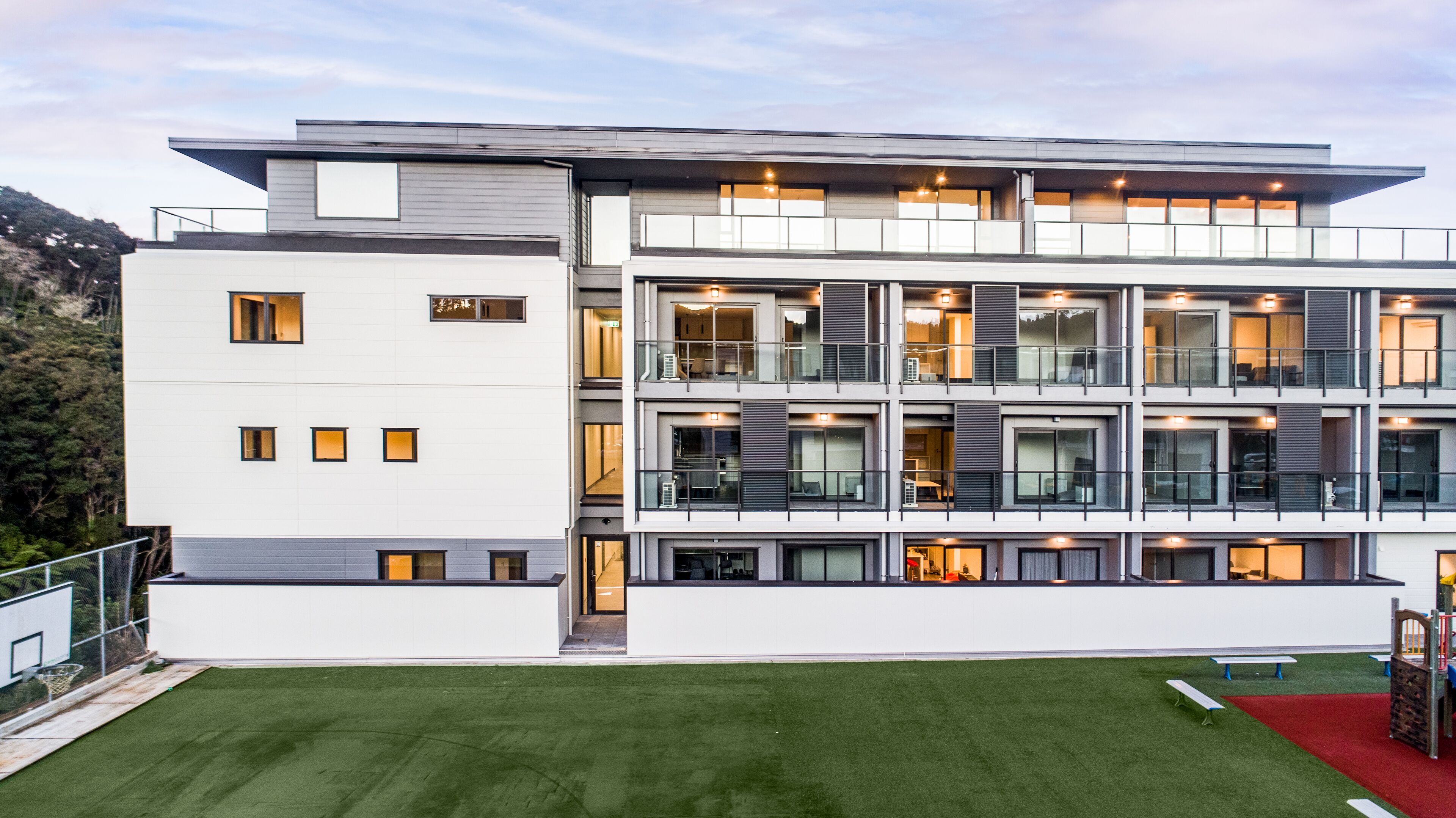 A modern multi-story building with a flat roof, large windows, and balconies.