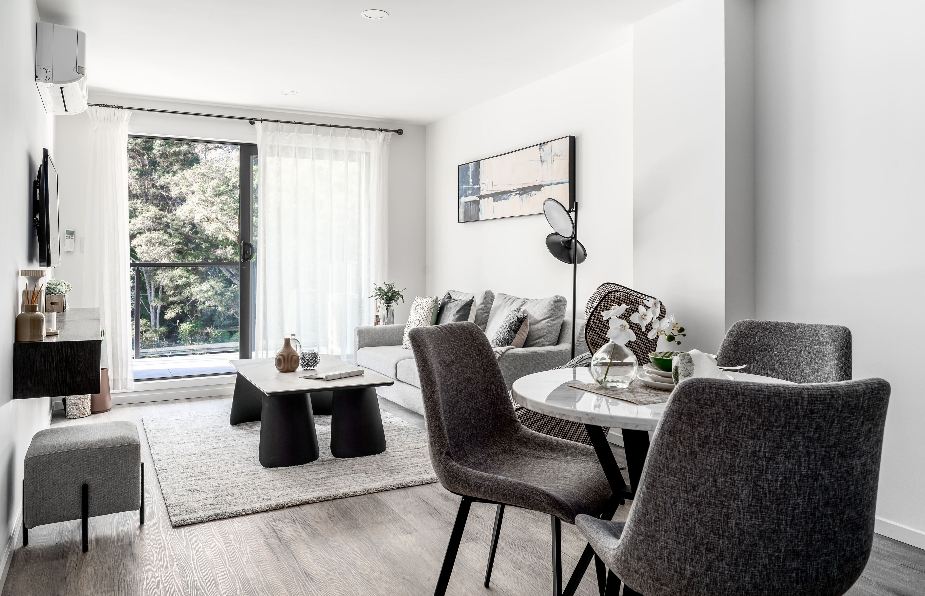 A modern living room with a sofa, a dining table with chairs, a coffee table, and a TV.