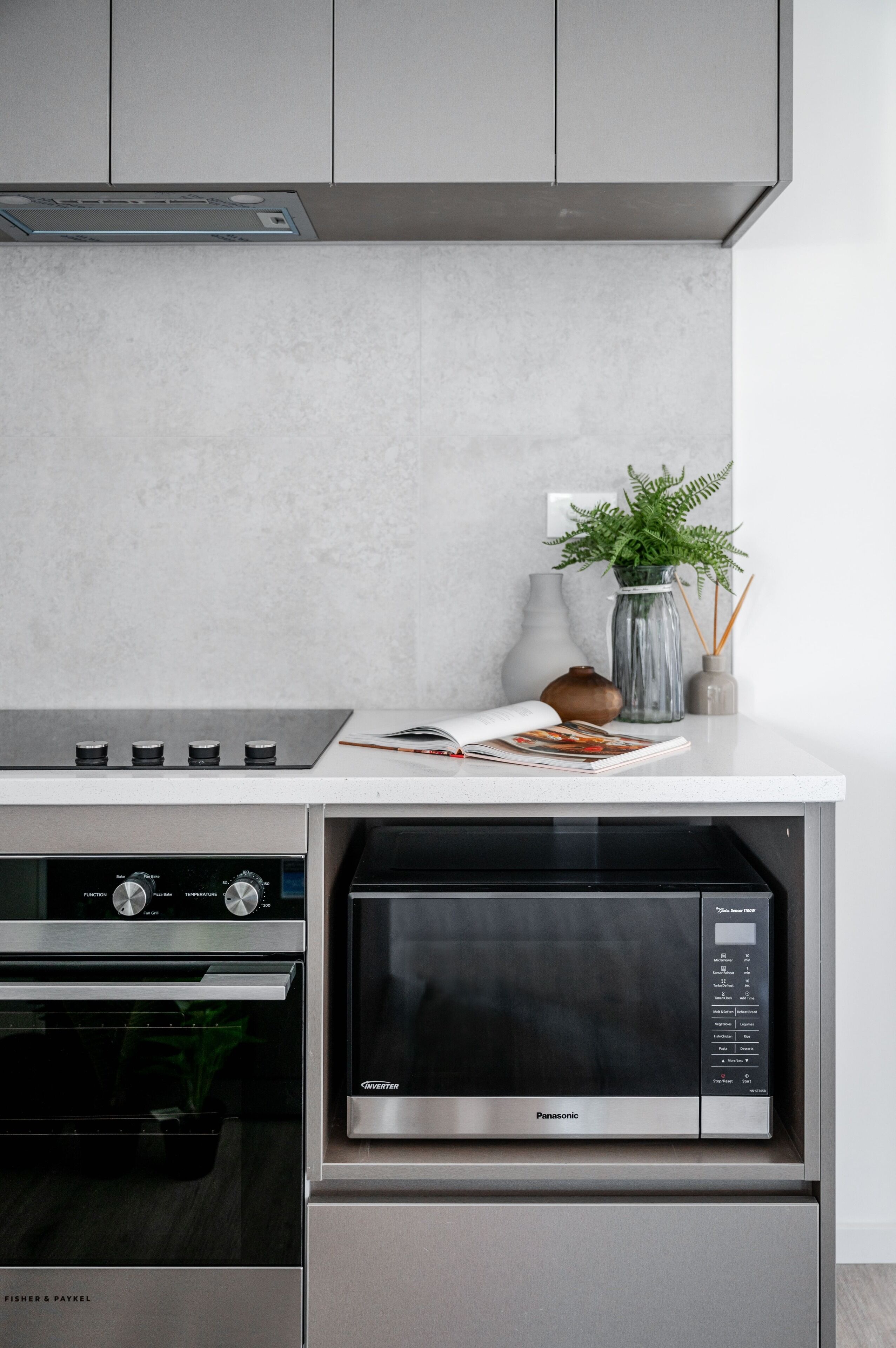Cozinha com forno embutido, micro-ondas e bancada branca.