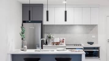 A modern kitchen with a central island, pendant lighting, and a built-in oven.