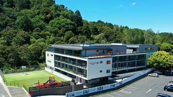 A modern building with a playground, surrounded by lush greenery.