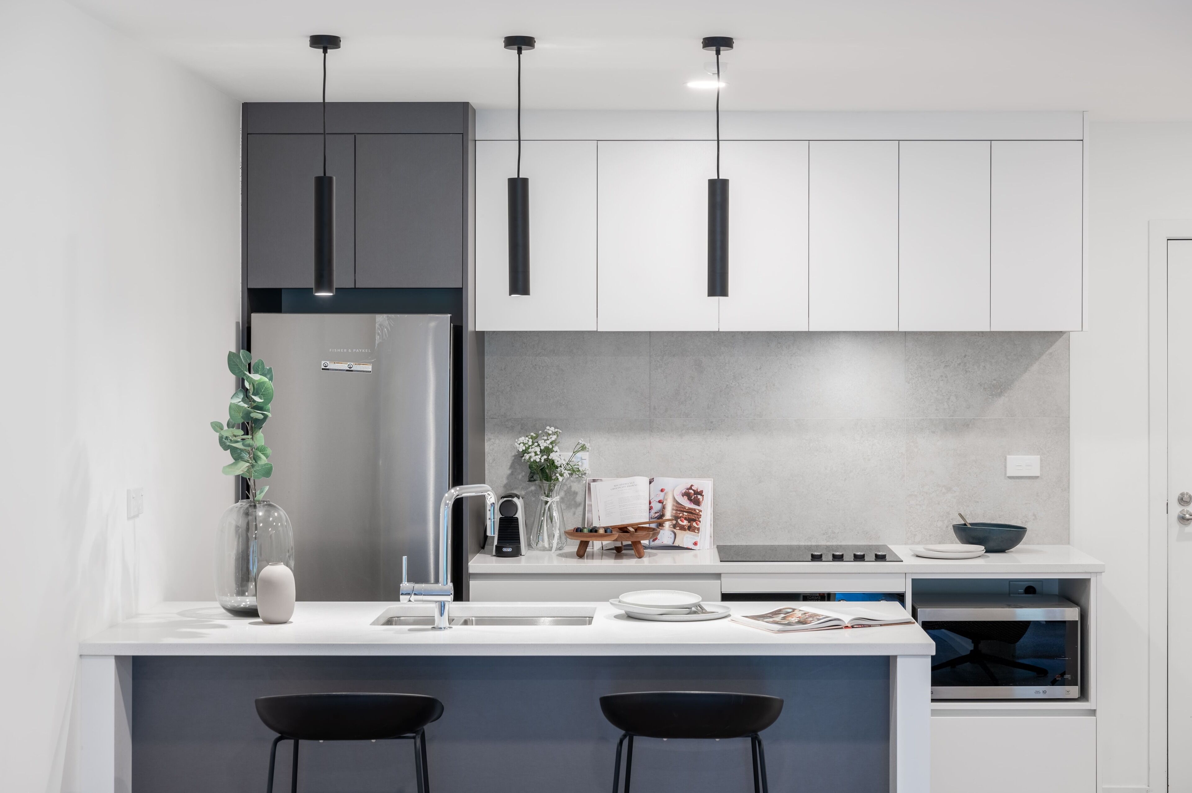 Une cuisine moderne dotée d’un îlot central, de luminaires suspendus et d’un four encastré.