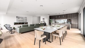 Une cuisine moderne avec un coin repas, comprenant un grand îlot central, des appareils électroménagers intégrés et un design minimaliste.