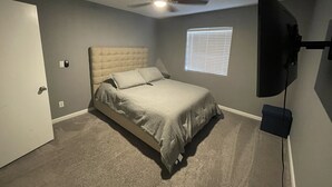 A bedroom with a bed, a ceiling fan, a window with blinds, and a TV mounted on the wall. - Sweet Little Paradise - Short Term / Long Term Renting   (Phoenix)