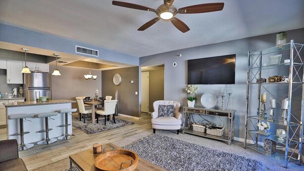 A modern living room with a dining area, a kitchen, and a TV mounted on the wall. - Sweet Little Paradise - Short Term / Long Term Renting   (Phoenix)