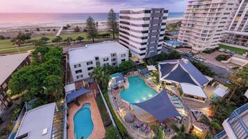 Una piscina al aire libre, sombrillas, sillones reclinables de piscina