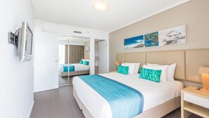 A hotel room with a large bed, a bedside table, a TV, and a mirror. - Club Wyndham Kirra Beach, Trademark Collection by Wyndham (Coolangatta)