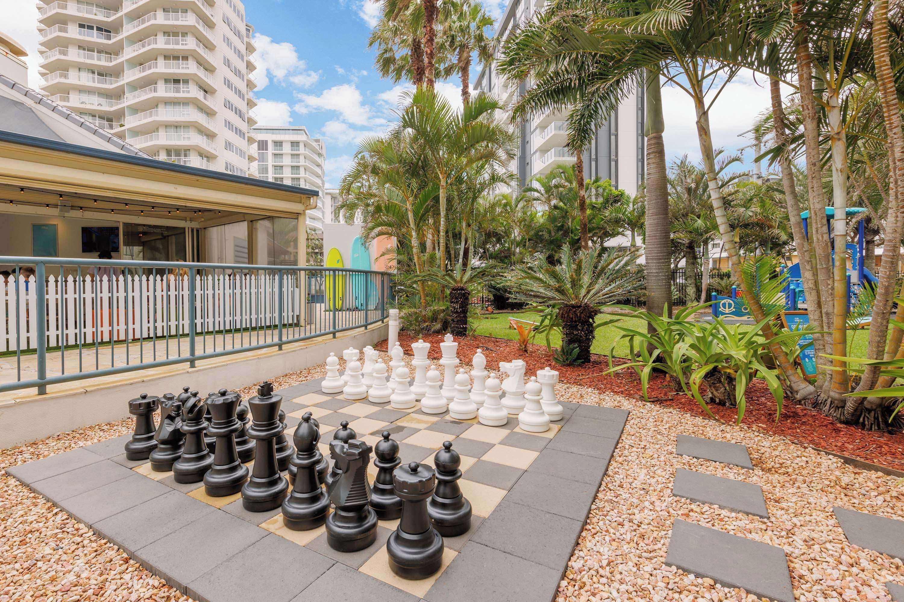 A chessboard set up outdoors with a building in the background.