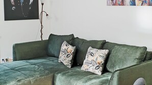 A green sectional sofa with two decorative pillows, a round white coffee table, and a grey armchair. - Lovingly furnished guest apartments Alpirsbach - Apartment 1 (Alpirsbach)