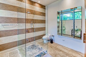 Features a large glass-enclosed shower, separate toilet area, and large mirror.