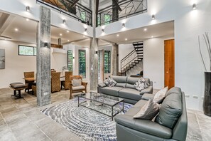 Relax in this stylish living area with a comfortable sofa, dining space, and staircase leading to an upper level.