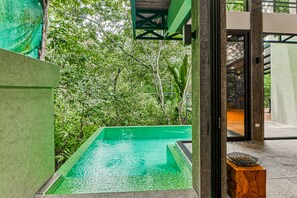 Relax by the serene pool surrounded by lush greenery and an area with a wooden bench.