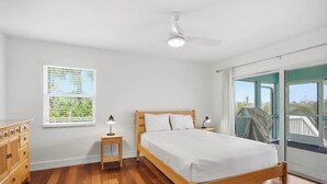 Ein Schlafzimmer mit einem hölzernen Bett, einem Nachttisch, einer Kommode, einem Deckenventilator und einem Fenster mit Jalousien.