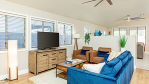 A modern living room with a large flat-screen TV, a blue sofa, and a wooden cabinet. - Golf and Backyard Getaway (Mesa)