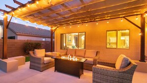 An outdoor patio with wicker furniture, a fire pit, and string lights. - Golf and Backyard Getaway (Mesa)