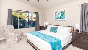 A bedroom with a bed, a chair, a nightstand, a dresser, a ceiling fan, a window with curtains, and a painting on the wall. - Golf and Backyard Getaway (Mesa)
