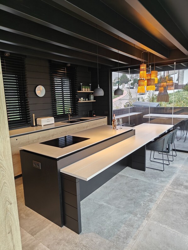 A modern kitchen with a central island, black cabinetry, and a large window overlooking a street. - Estepona - Sleeps 8 - Pool - Pet Friendly - Garden (Estepona)
