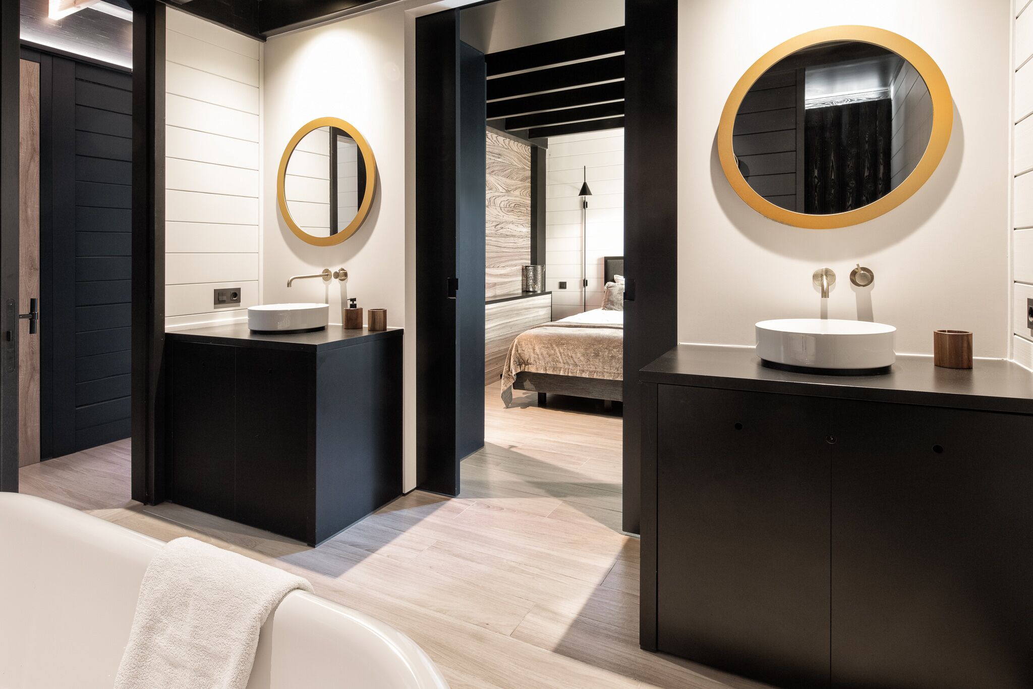 Un baño moderno con un espejo grande, una bañera y un tocador con lavabo.