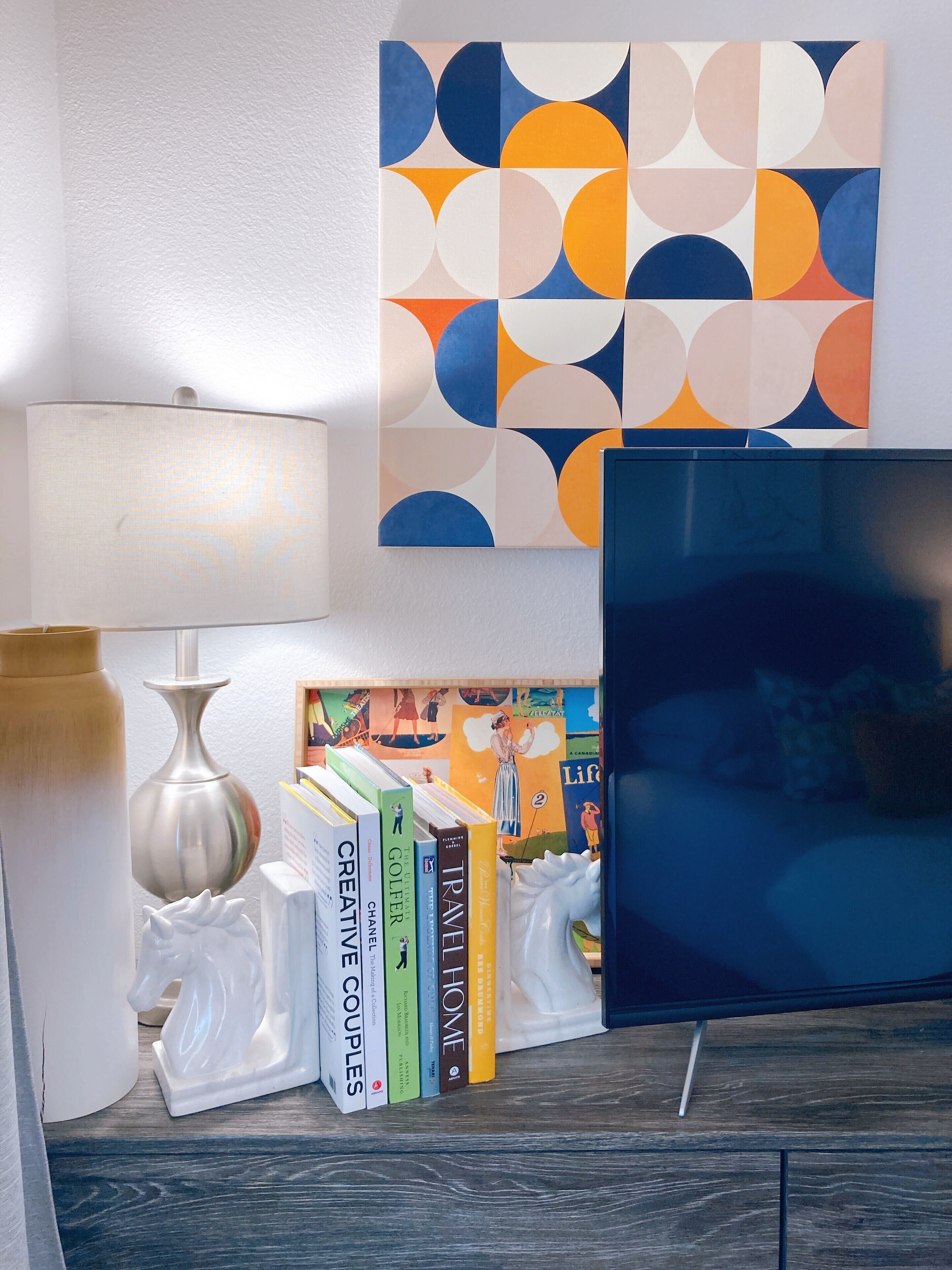 Un salon avec une télévision moderne, une lampe et une bibliothèque remplie de livres.