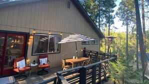 A wooden deck with a table and chairs, a red chair, and a hanging chair.