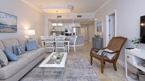 Een moderne woonkamer met een bank, salontafel en een eethoek met stoelen.