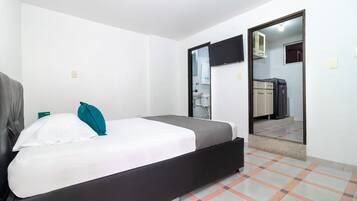 Un dormitorio con cama, armario, espejo y baño a la vista a través de una puerta abierta.