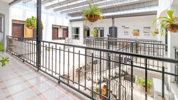A spacious atrium with a high ceiling, multiple levels, and hanging planters. - Ayenda Oporto Suites (San José de Cúcuta)