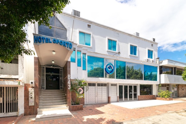 A hotel named "HOTEL OPORTO" with a modern facade, large windows, and a visible entrance. - Ayenda Oporto Suites (San José de Cúcuta)