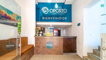 A hotel reception area with a blue sign reading "HOTEL OPORTO SUITES CUCUTA BIENVENIDOS".