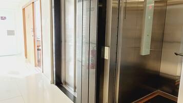 An elevator with a digital display, a door with a handle, and a tiled floor.