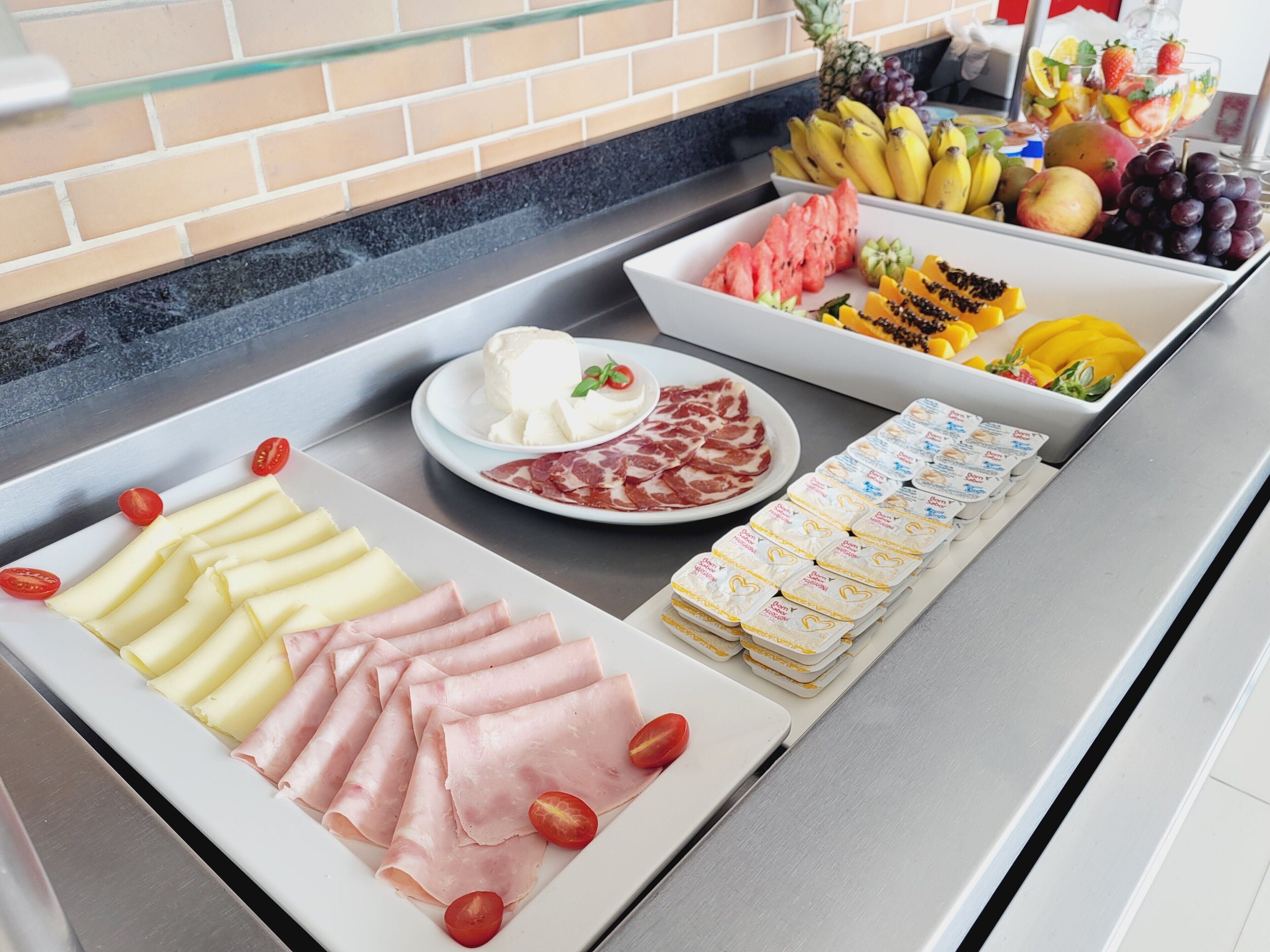 Un bufé con diversos alimentos, incluyendo queso, carnes, frutas y productos lácteos.