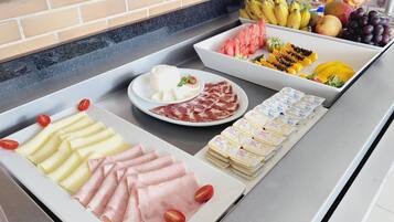 Un bufé con diversos alimentos, incluyendo queso, carnes, frutas y productos lácteos.