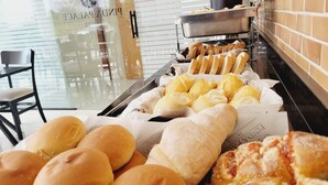 Un bufé con diversas opciones de panadería, incluyendo panecillos y pastelería.