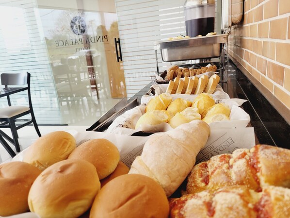 Un bufé con diversas opciones de panadería, incluyendo panecillos y pastelería.