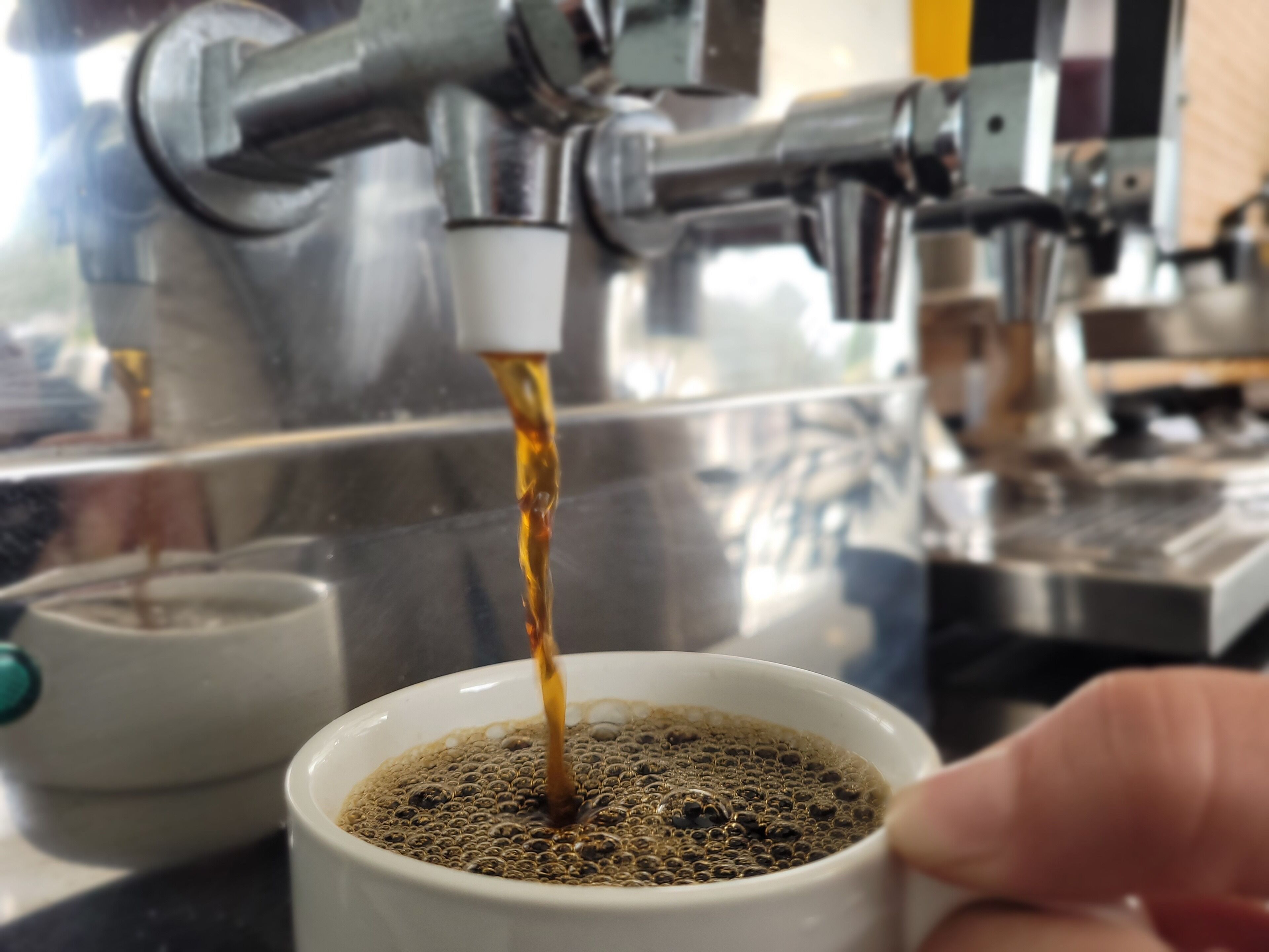 Una cafetera sirviendo café en una taza.