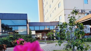 Un edificio moderno con amplios ventanales y un pequeño jardín con flores rosadas.