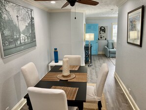 A dining area with a black table, white chairs, and a blue water bottle on a white side table. - Montrose Hist Dist - CharmAzure 2 Br/1Ba w W/D apt (Houston)