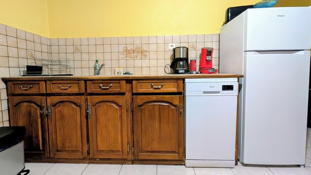 Une cuisine avec des meubles de rangement en bois, un lave-vaisselle, une machine à café et un réfrigérateur.