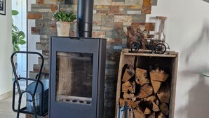 A modern living room with a wood-burning stove, a stone wall, and a small wooden table with a bicycle and a vase. - Charm restored (SEUR)