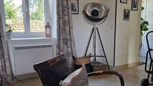 A cozy living room with a vintage-style chair, a floor lamp, and a window with curtains. - Charm restored (SEUR)