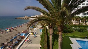 A beachside hotel with a pool, palm trees, and a view of the sea. - Apartment on the Beach with Sea Views, Balcony, Shared Pool & WiFi (Nerja)