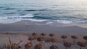 A beach with waves, a sandy shore, and thatched umbrellas. - Apartment on the Beach with Sea Views, Balcony, Shared Pool & WiFi (Nerja)