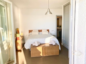 A bedroom with a bed, bedside table, lamp, and a view into the bathroom. - Apartment with Sea Views, Beachfront, Shared Pool, A/C and WiFi (Nerja)