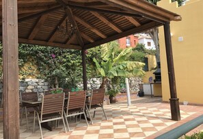 Un'area salotto all'aperto coperta, con panche in legno e pavimento a scacchi.