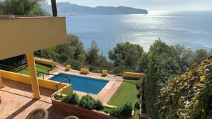 A pool area with a view of the sea, outdoor furniture, and a landscaped garden. - Villa "Casa Heidi" with Sea View, Pool, Balcony, Air Conditioning & Wi-Fi (Almunecar)