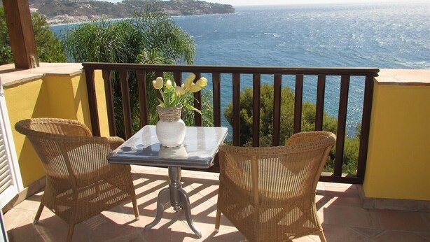 A balcony with wicker chairs, a small table, and a vase with flowers. - Villa "Casa Heidi" with Sea View, Pool, Balcony, Air Conditioning & Wi-Fi (Almunecar)